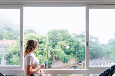 Young woman having morning coffee by the window