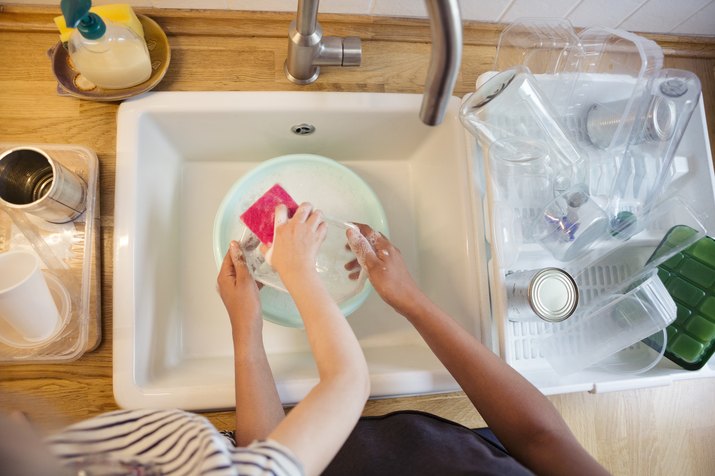 Child and adult washing household plastic containers for recycling or reuse