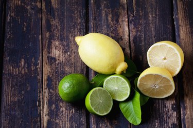 Whole and sliced lemons and limes on dark wood