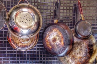 Saucepans And Kitchen Utensils Hanging On Backsplash At Home