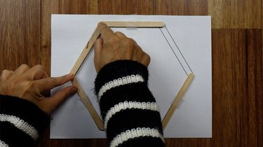 Gluing popsicle sticks for DIY hexagon shelves.