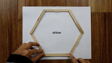 Gluing popsicle sticks for DIY hexagon shelves.