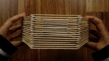 Gluing popsicle sticks for DIY hexagon shelves.