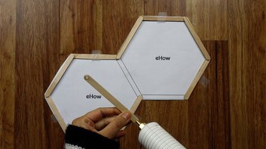 Gluing popsicle sticks for DIY hexagon shelves.