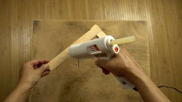 Gluing wood stir sticks to tabletop in herringbone pattern.