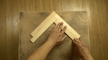 Gluing wood stir sticks to tabletop in herringbone pattern.