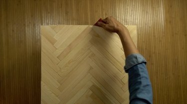 Sanding edges of DIY herringbone pattern tabletop using paint sticks.