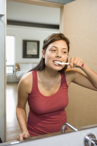 Young woman brushing teeth in bathroom