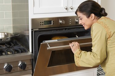 Woman checking on Thanksgiving turkey in oven