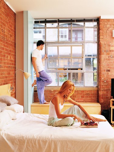 Woman Reading in Bed with a Man Looking out the Window