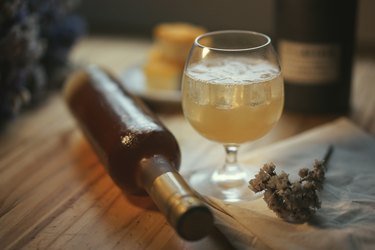 cocktail with a reclining bottle and sprig of herbs in the foreground