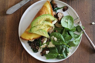 Vegetarian omelet with sauteed mushrooms, onions and spinach served on a plate.